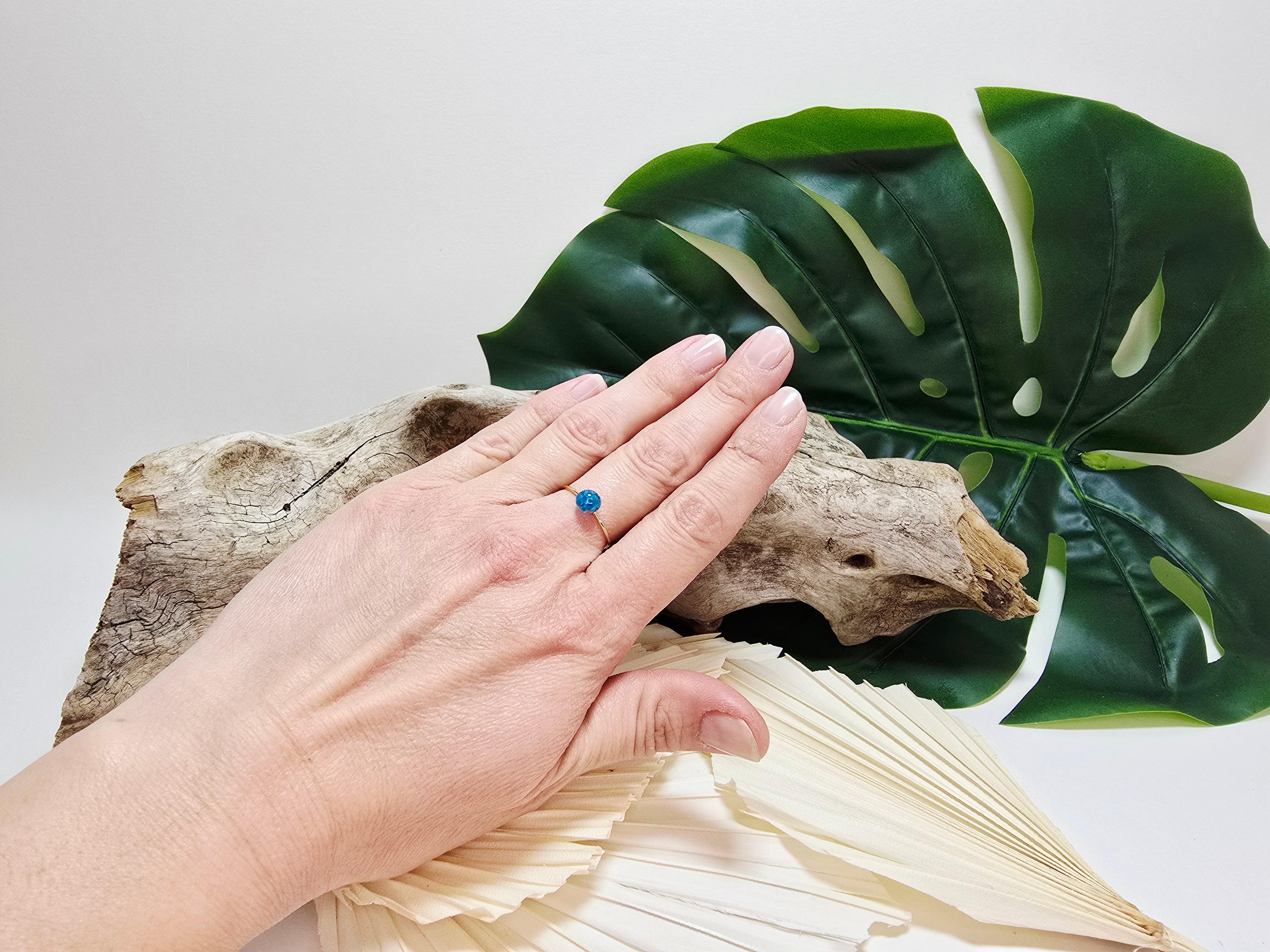Mira - bague portée au doigt, vue lifestyle sur bois flotté et monstera